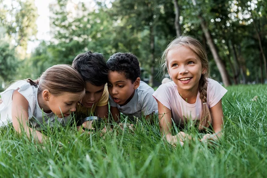 Children-in-grass-looking-through-magnifying-glass